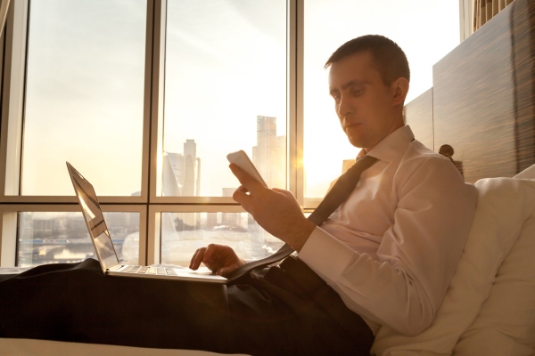 Young businessman with electronic devices in hotel